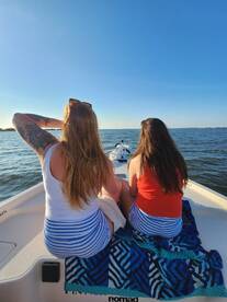 Two friends enjoy a sunny day on a boat, taking in the beautiful water views — a perfect moment for relaxation and camaraderie.