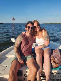 A happy couple enjoys a sunny day on the boat, capturing a perfect moment of joy and relaxation on the water.
