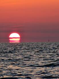 A breathtaking sunset over the ocean, showcasing vibrant colors and serene waters — perfect for capturing the beauty of nature during a boat trip.