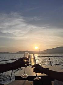 A couple toasts with champagne glasses against a stunning sunset backdrop, creating a romantic atmosphere perfect for sunset cruises.