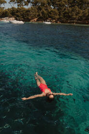 A woman floats serenely in crystal-clear waters, enjoying a perfect day of swimming and relaxation under the sun.