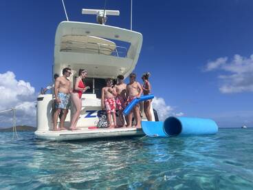 A lively group of friends and family enjoys a fun day on the water, preparing to slide into the ocean from their boat — perfect for summer adventures and family outings.