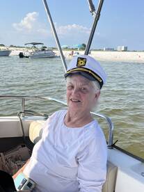 A cheerful woman wearing a captain's hat enjoys a sunny day on the boat, embodying the spirit of adventure and fun on the water.