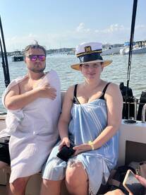 A couple enjoys a sunny day on a boat, showcasing a relaxed atmosphere with playful hats and towels — perfect for summer outings on the water.