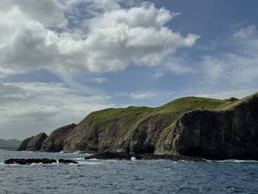 A stunning view of a rugged coastline with lush green hills under a partly cloudy sky, perfect for showcasing the natural beauty of the region.