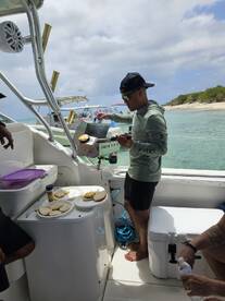 A chef prepares food on a grill aboard a boat, showcasing onboard dining amenities and a relaxed atmosphere for guests.