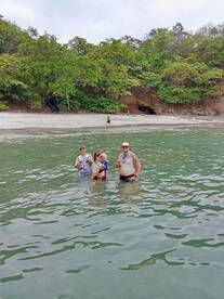 A joyful group enjoys a refreshing swim in shallow waters, celebrating together at a beautiful beach location.