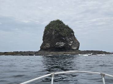 A scenic view of a rocky formation emerging from the ocean, captured from a boat — perfect for showcasing the natural beauty of coastal landscapes.