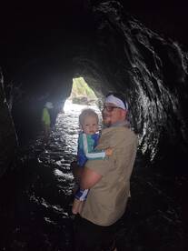 A father holds his child while exploring a cave, creating memorable family moments in a stunning natural setting.
