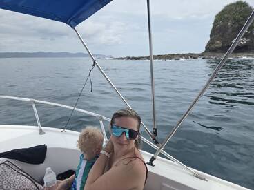 A mother enjoys a scenic boat ride with her child, capturing a moment of family bonding on the water amidst beautiful coastal views.