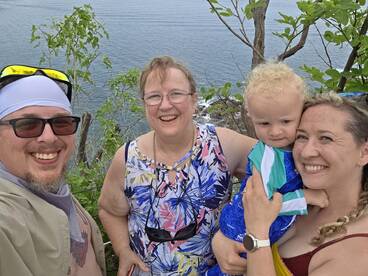 A joyful family poses for a selfie with the ocean in the background, capturing a memorable moment during their adventure.