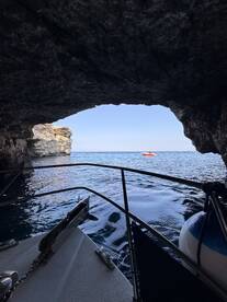 A scenic view from inside a cave, showcasing the tranquil waters and a distant boat outside — perfect for exploring coastal wonders.