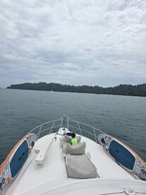 A child enjoys the view from the front of a boat, with a paddleboard visible alongside — a perfect moment for family adventures on the water.