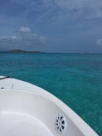A stunning view from the bow of a boat, showcasing the vibrant turquoise waters and a distant island, perfect for a day of exploration and relaxation on the water.