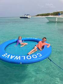 Two children enjoy a fun day on a floating mat in crystal-clear waters, perfect for family adventures and beach outings.