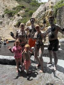 A joyful family enjoys a mud bath experience, showcasing their playful side while covered in mud — a fun and memorable activity during their adventure.