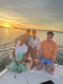 A joyful family poses together on a boat at sunset, capturing a perfect moment of togetherness and celebration on the water.