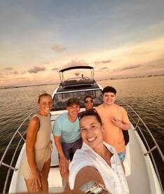 A joyful group poses for a selfie on a boat during sunset, capturing a memorable moment on the water — perfect for family outings or celebrations.