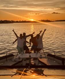 A lively group celebrates at sunset aboard a yacht, capturing the joy of a perfect evening on the water.