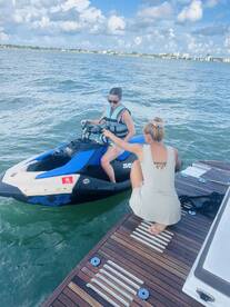 Two women prepare for an exciting jet ski ride on the water, showcasing the thrill of water sports and adventure on a sunny day.