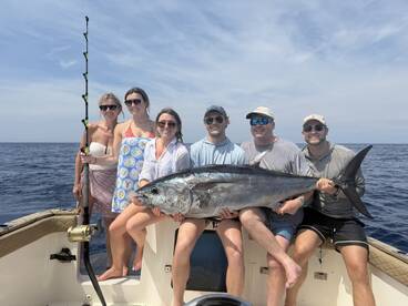 A group of friends proudly displays their impressive catch while fishing at sea, capturing the excitement of a successful day on the water.