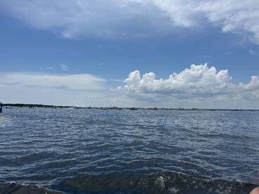 A scenic view of the water under a partly cloudy sky, capturing the essence of a tranquil day on the water.