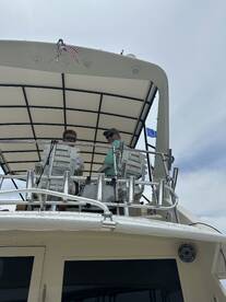 Two individuals are seen at the helm of a boat, showcasing the interior space and control area, perfect for navigating the waters.
