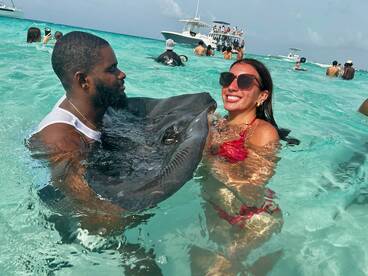 A couple interacts with a stingray in the clear waters, showcasing a unique wildlife experience — perfect for adventure seekers in the Bahamas.