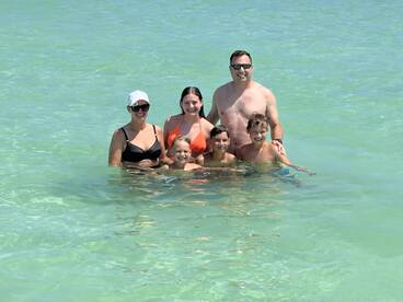 A joyful family enjoys a fun day swimming together in crystal-clear waters, creating lasting memories at the beach.