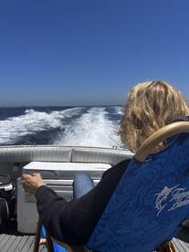 A guest enjoys a relaxing moment on a boat, taking in the scenic views while cruising through the open water — perfect for unwinding on a sunny day.