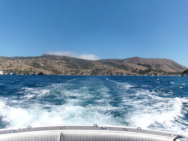 A stunning view of the coastline and hills while underway on a boat, showcasing the beauty of the island landscape.