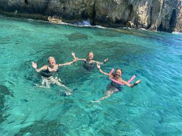 Three friends enjoy a refreshing swim in crystal-clear waters, celebrating a perfect day on the water — ideal for summer adventures and group outings.