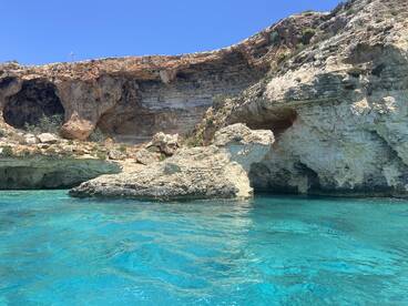 A stunning view of rocky cliffs and crystal-clear turquoise waters, showcasing the natural beauty of the coastline — perfect for scenic boat tours and exploration.