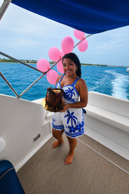 A woman celebrates with a birthday cake on a boat, surrounded by festive pink balloons — perfect for memorable celebrations on the water.