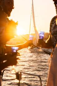 Guests celebrate with cocktails at sunset aboard a sailboat, creating a picturesque moment perfect for memorable sailing experiences.