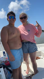 Two young individuals pose together on a boat, enjoying a sunny day on the water — a perfect moment for summer adventures.