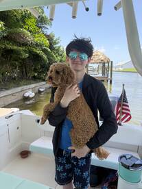 A young boy smiles while holding a dog on a boat, capturing a joyful moment on the water — perfect for family outings and pet-friendly adventures.