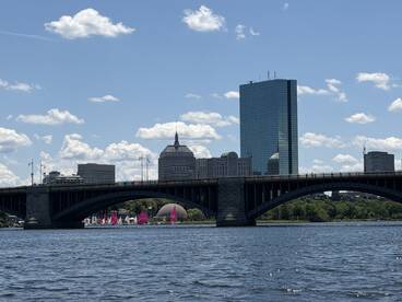 A picturesque view of a city skyline featuring a bridge and colorful sailboats on the water, perfect for showcasing urban boating adventures.