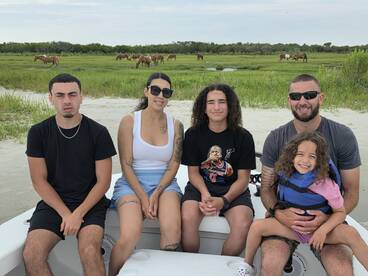 A family enjoys a day on the boat, with wild horses grazing in the background — a perfect blend of adventure and nature.