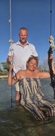 A joyful couple enjoys swinging in shallow water, capturing a fun moment during their boating adventure — perfect for memorable experiences on the water.
