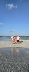 A cheerful group poses together on a sandy beach, capturing a memorable moment during their boating adventure — perfect for family gatherings or friends' trips.