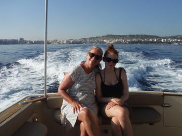 A joyful moment captured on a boat as two women enjoy a sunny day on the water, showcasing the beauty of their surroundings and the fun of boating.