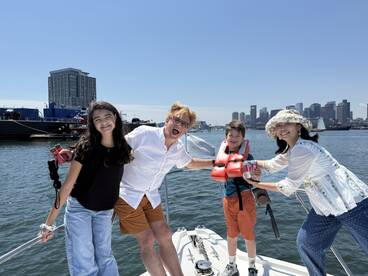 A joyful family poses on a boat with a stunning city skyline in the background, capturing a perfect moment of fun and togetherness on the water.