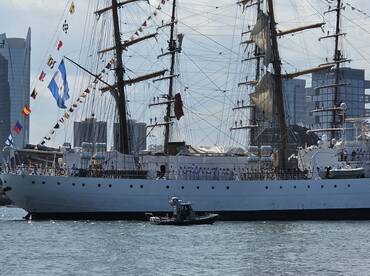 A majestic tall ship adorned with colorful flags, docked in the harbor, showcasing its impressive sails and crew. Perfect for maritime enthusiasts and sailing events.