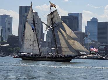 A majestic sailboat navigates the waters against a backdrop of a bustling city skyline, showcasing the beauty of maritime adventures.