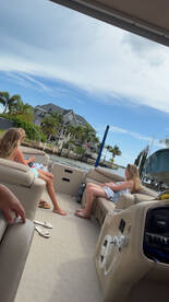 Two guests relax inside a pontoon boat, enjoying the scenic view of waterfront homes. Perfect for a leisurely day on the water.