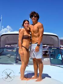 A couple poses on the deck of a yacht, enjoying a sunny day on the water — perfect for romantic getaways or summer adventures.