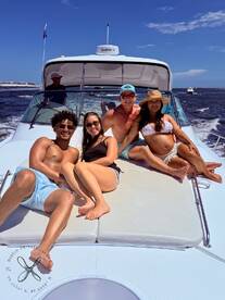 A fun group of friends relaxes on the deck of a boat, enjoying a sunny day on the water — perfect for summer adventures and memorable outings.