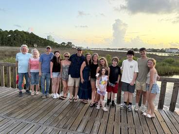 A joyful family gathers for a group photo at sunset, capturing a memorable moment by the water — perfect for family reunions or vacations.