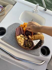A beautifully arranged charcuterie board featuring a variety of cheeses, meats, and snacks, perfect for enjoying on a boat trip.